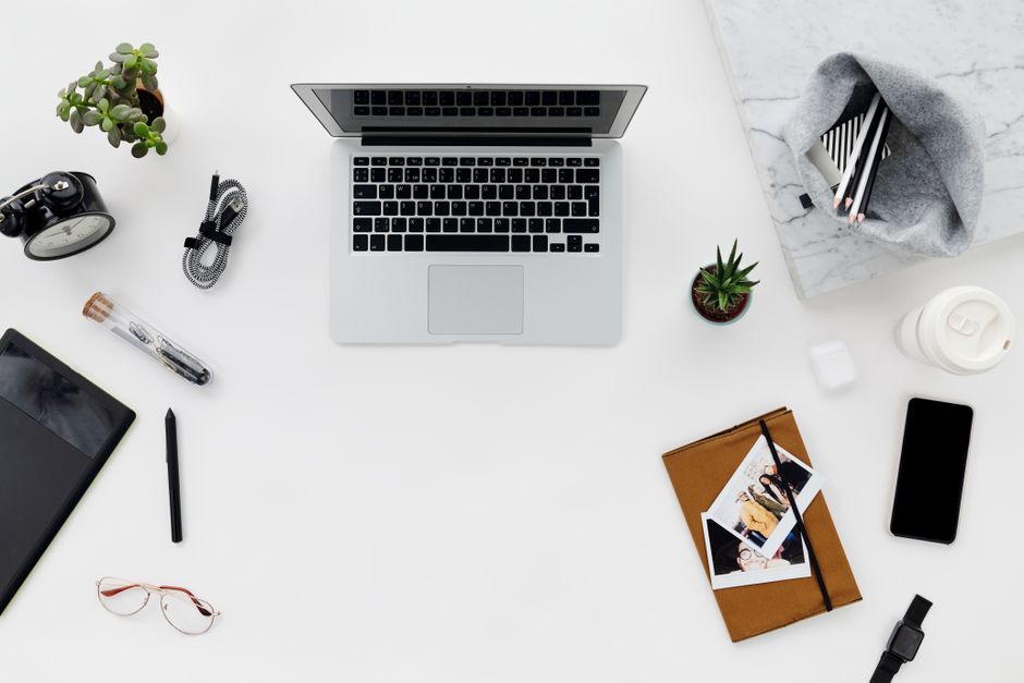 Top-down flat lay of laptop, phone, tablet and desk accessories — multiple devices on a workspace